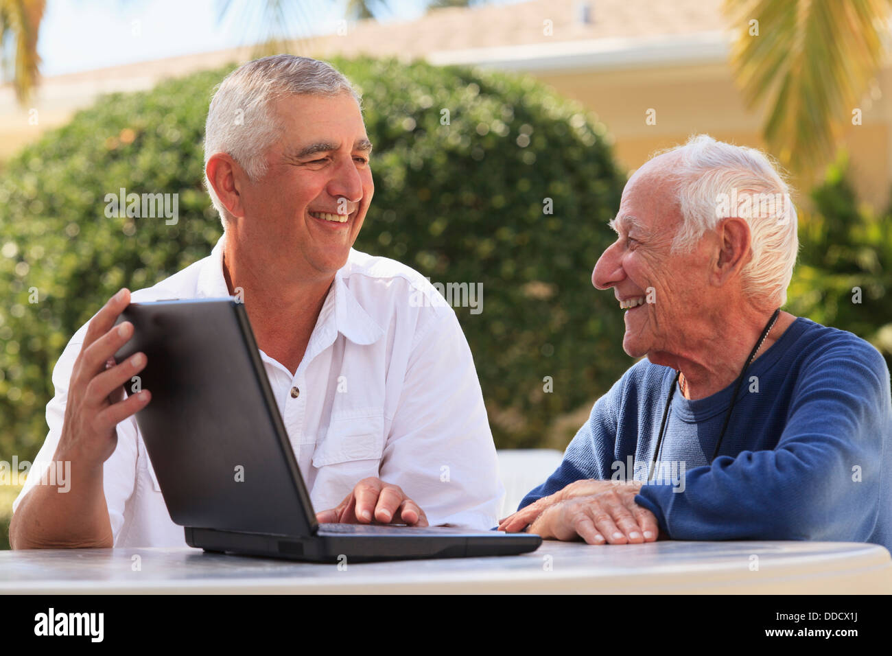 Senior man smiling showing a laptop to his father Stock Photo