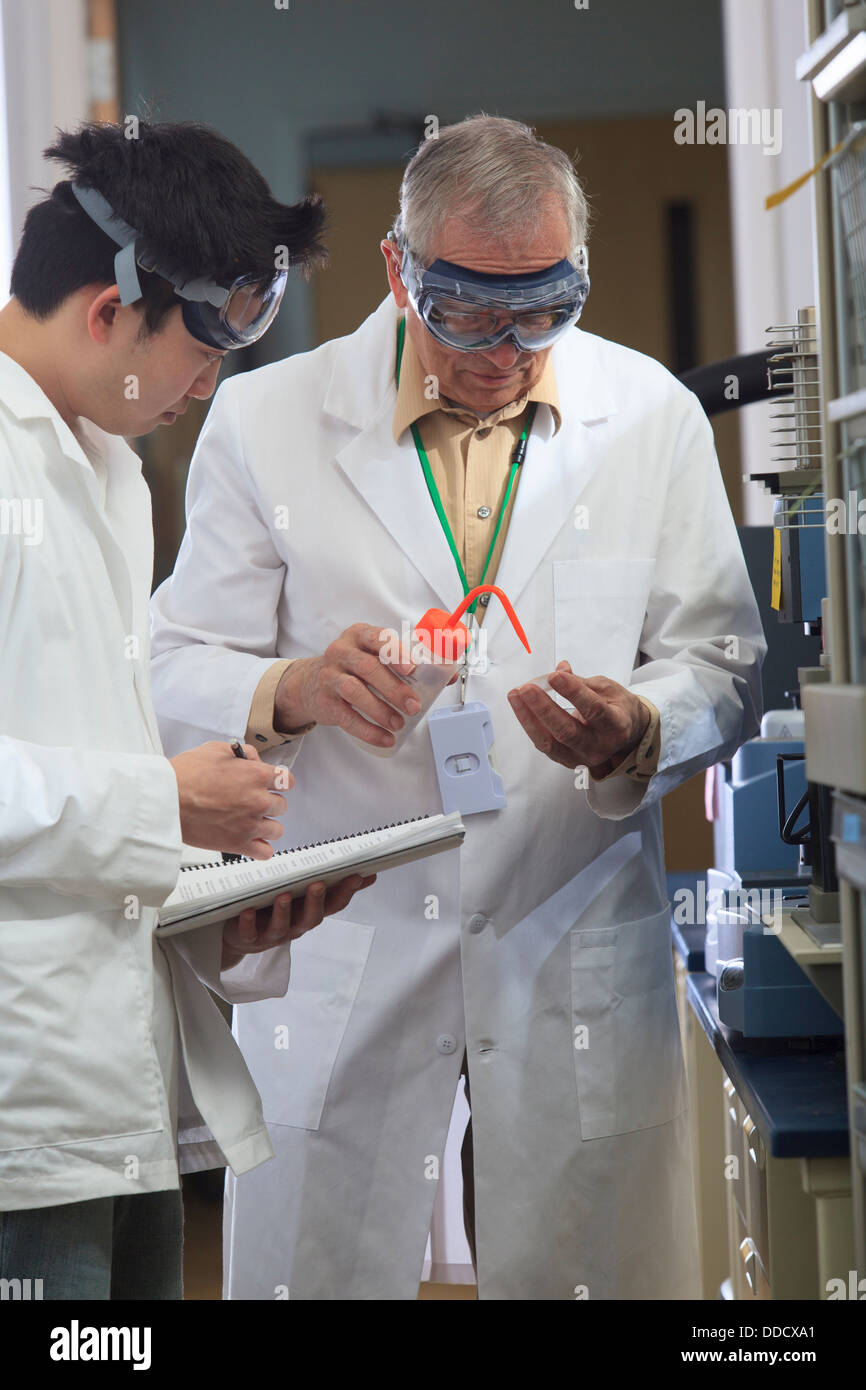 Professor working with engineering student adding ethanol to sample ...