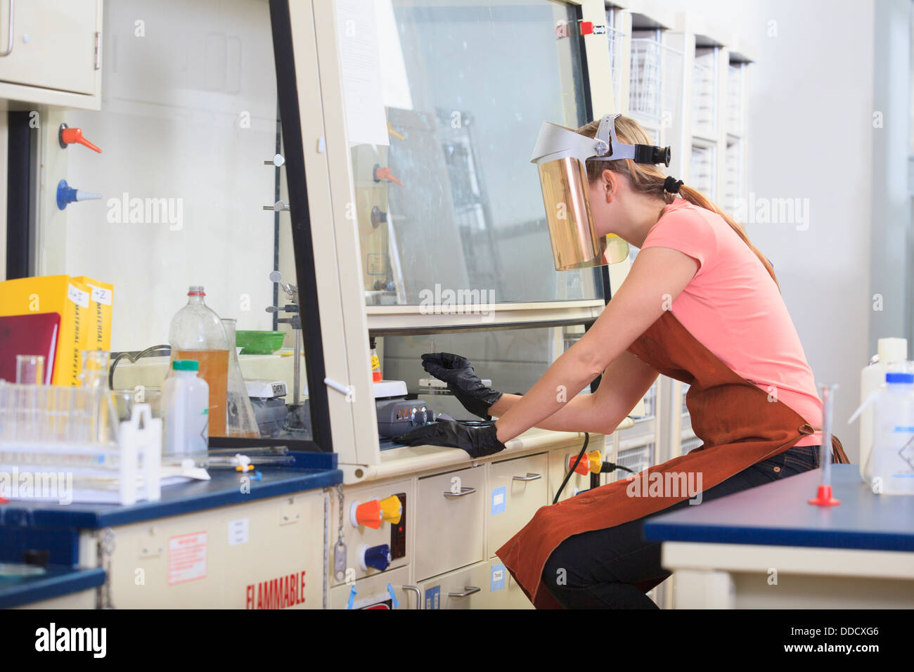 Engineering student wearing protective equipment while working on chemistry experiment in fume hood Stock Photo