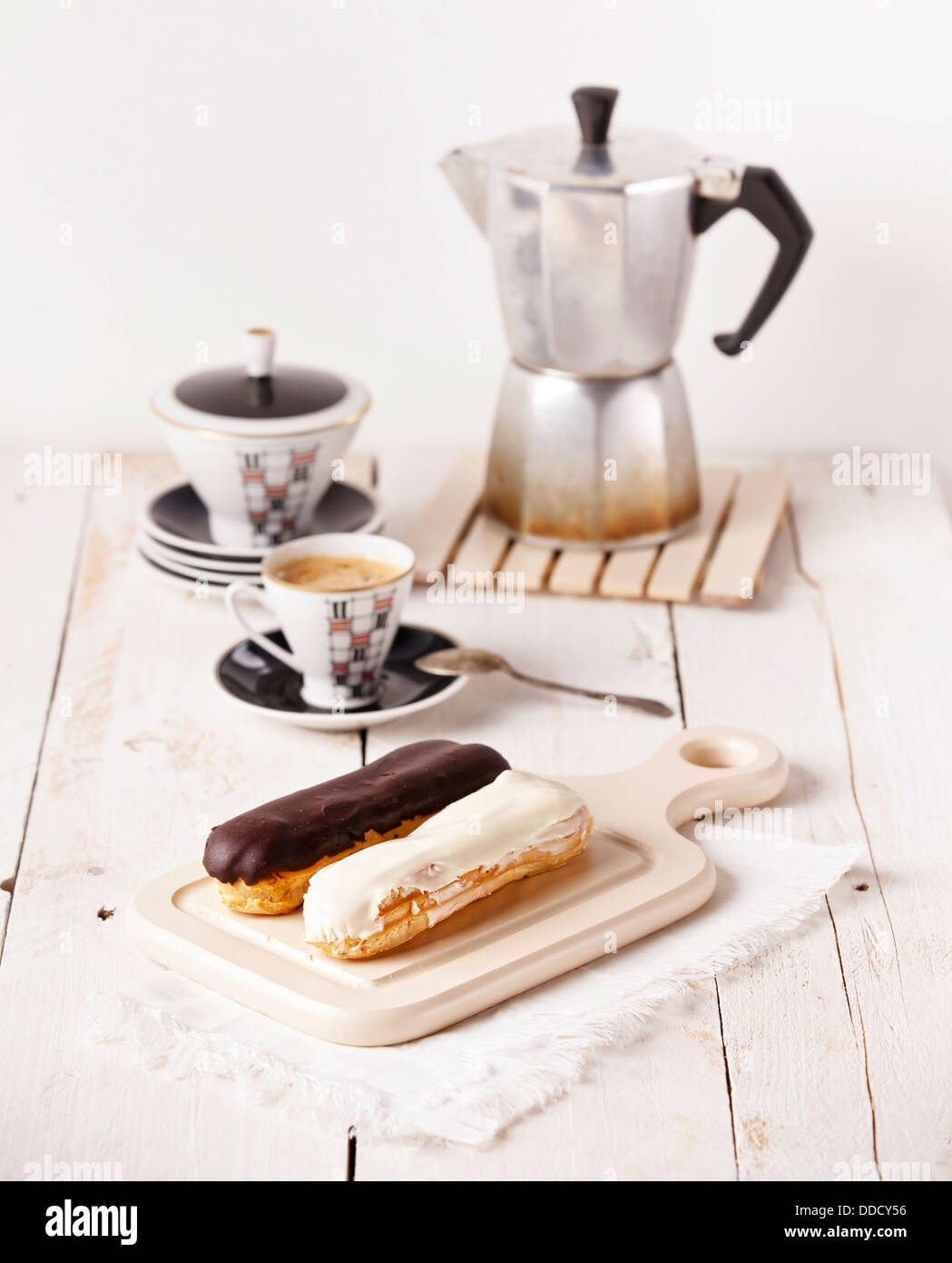 Chocolate eclairs on board on white textured background Stock Photo