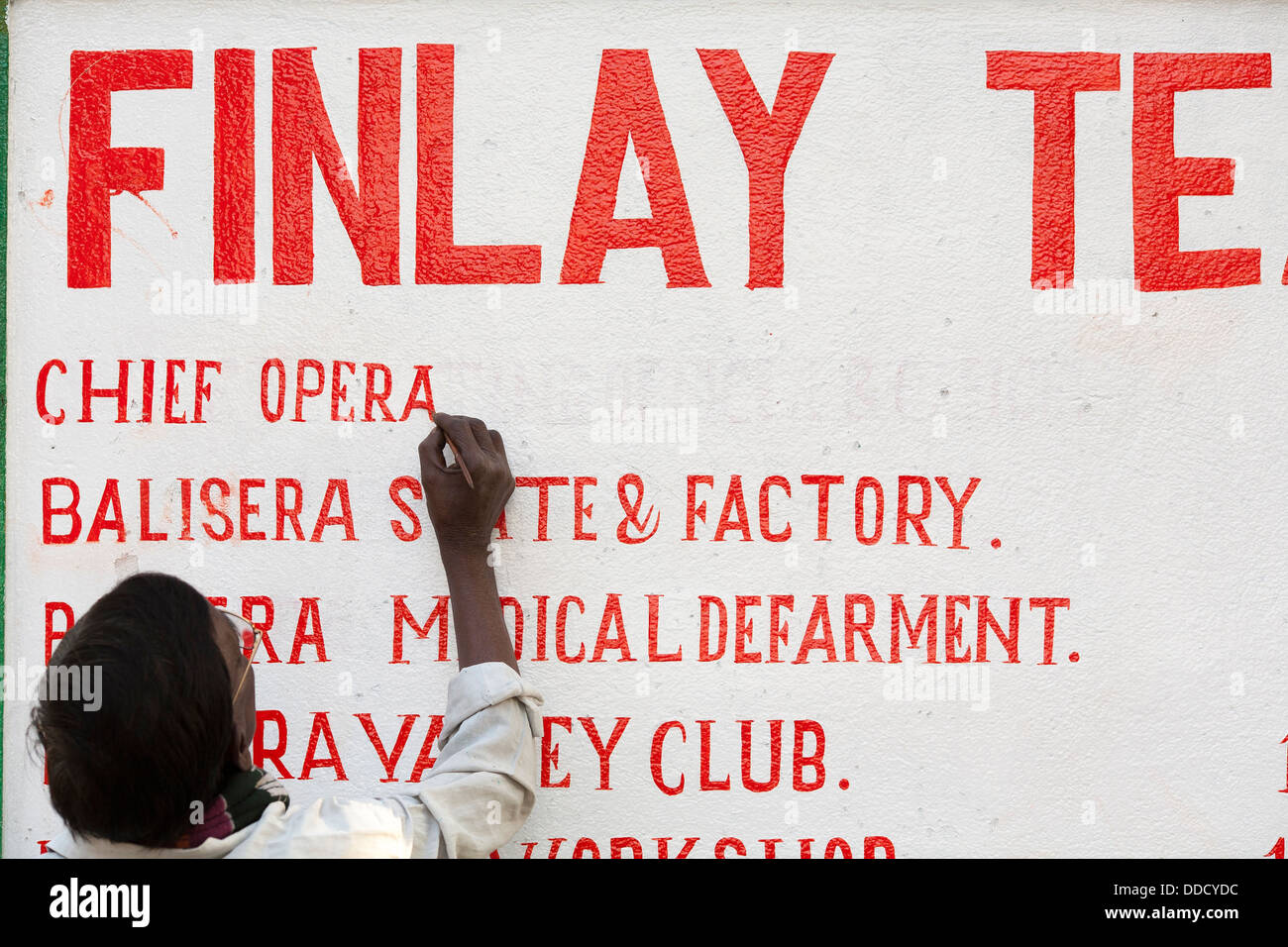 A sign maker paints by hand a directory of offices for the Finlay tea ...