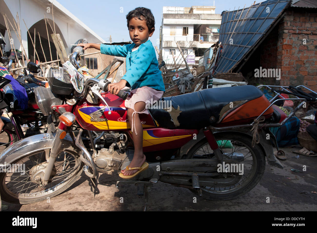 A small child sits astride a chinese motorbike  in the central market in Srimongol, Syhlet Division Bangladesh Stock Photo