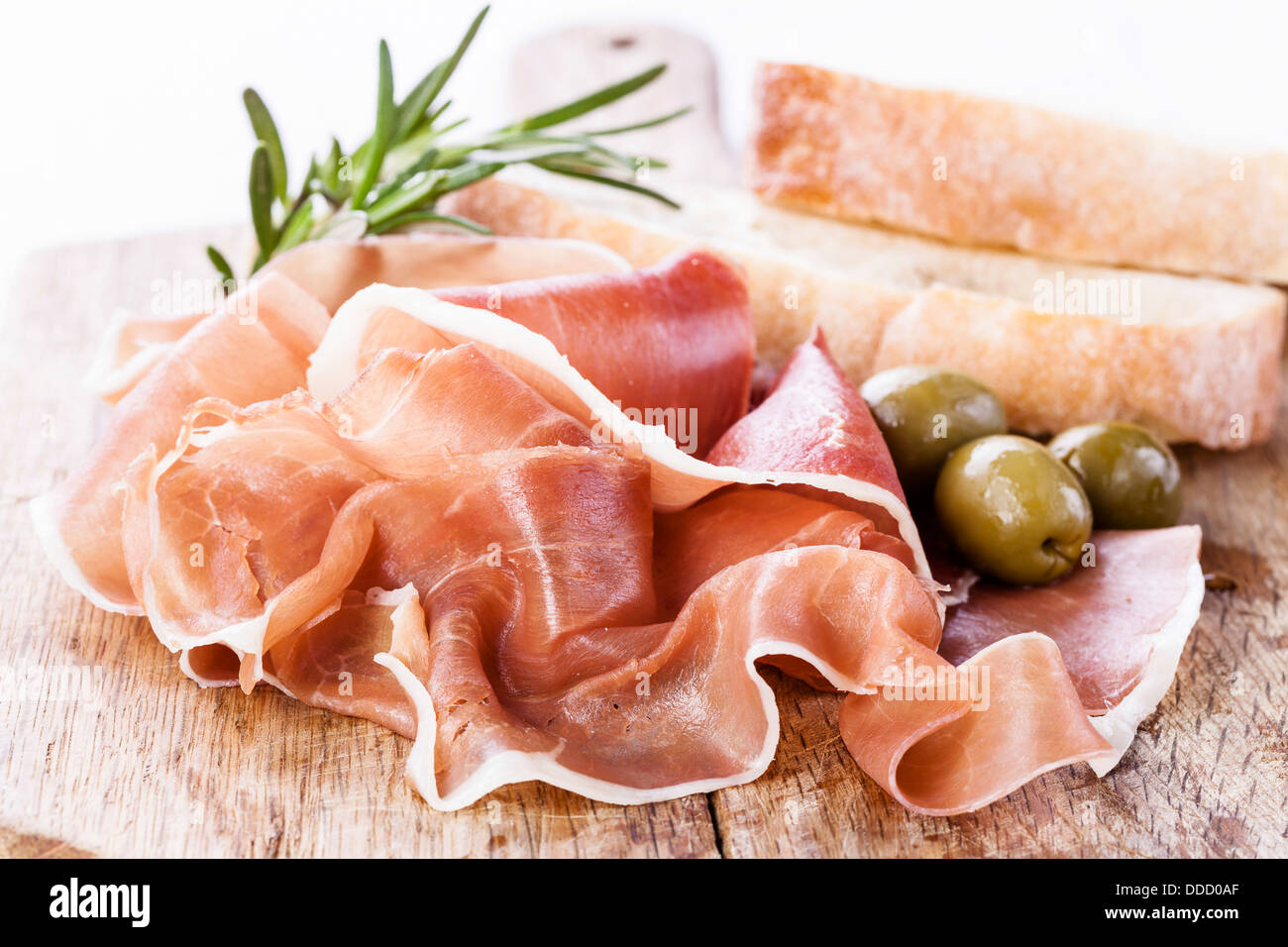 Ham with olives on wooden background Stock Photo