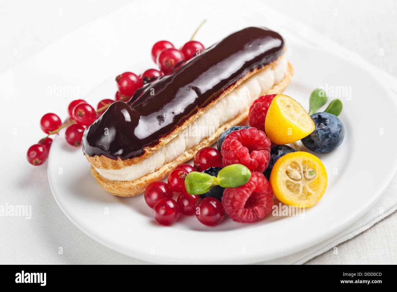 Chocolate eclair with berries on white plate Stock Photo