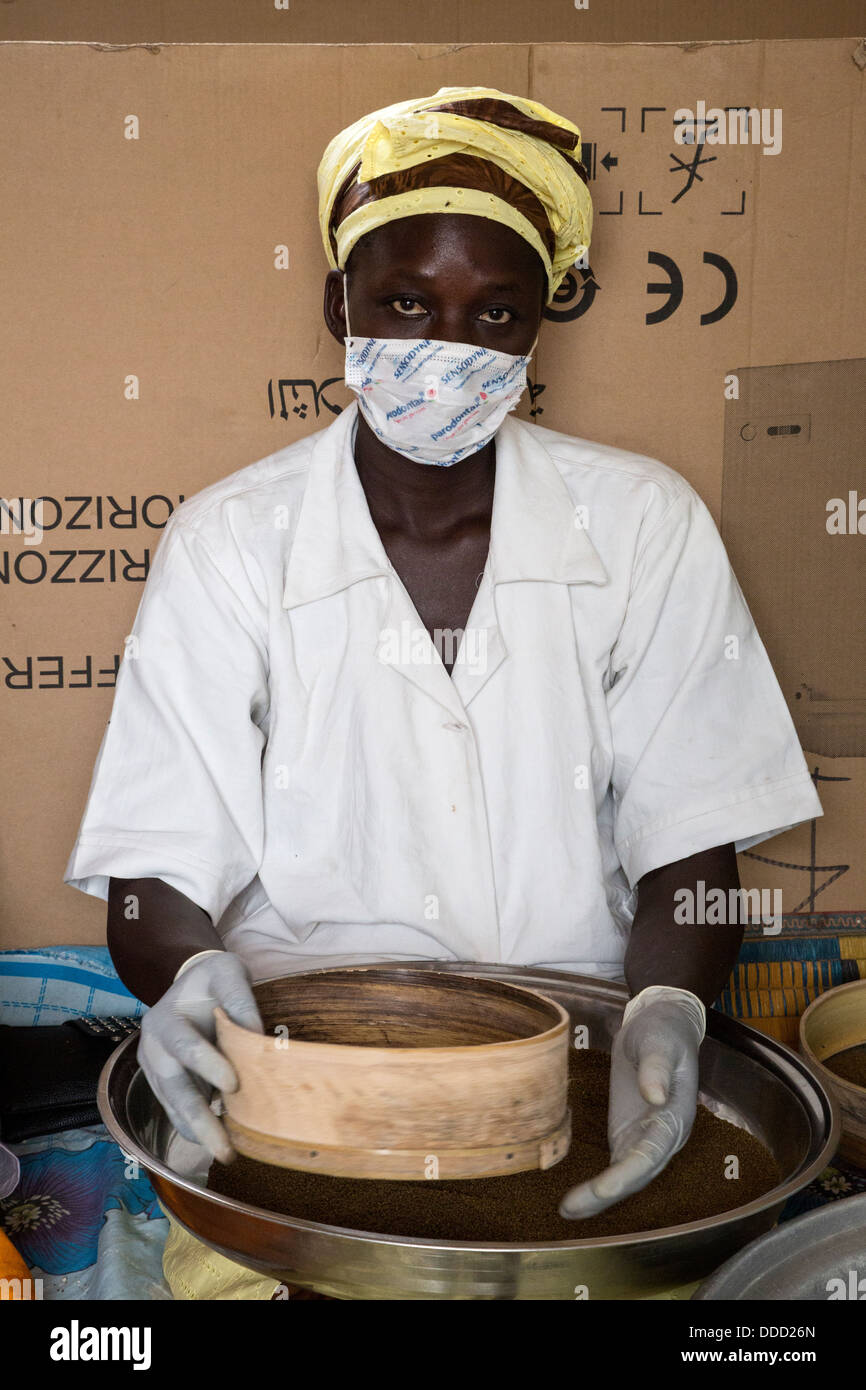 Staff Member of Millet Processing Facility Sifting Grain to Remove Debris, Kajmoor Village, Senegal. An Africare Project. Stock Photo