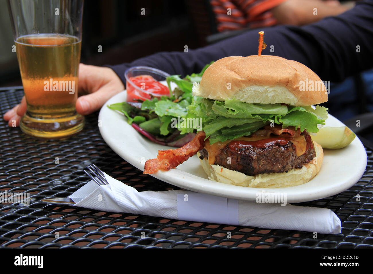Delicious bacon cheeseburger piled high with lettuce,side salad,pickle and chilled beer makes a great lunch at local brewery on a hot summer's day. Stock Photo
