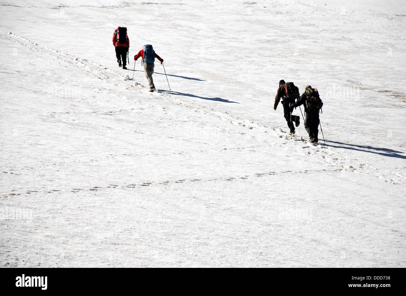 trekkers cross a steep snow slope high in the Fann mountains of Tajikistan Stock Photo