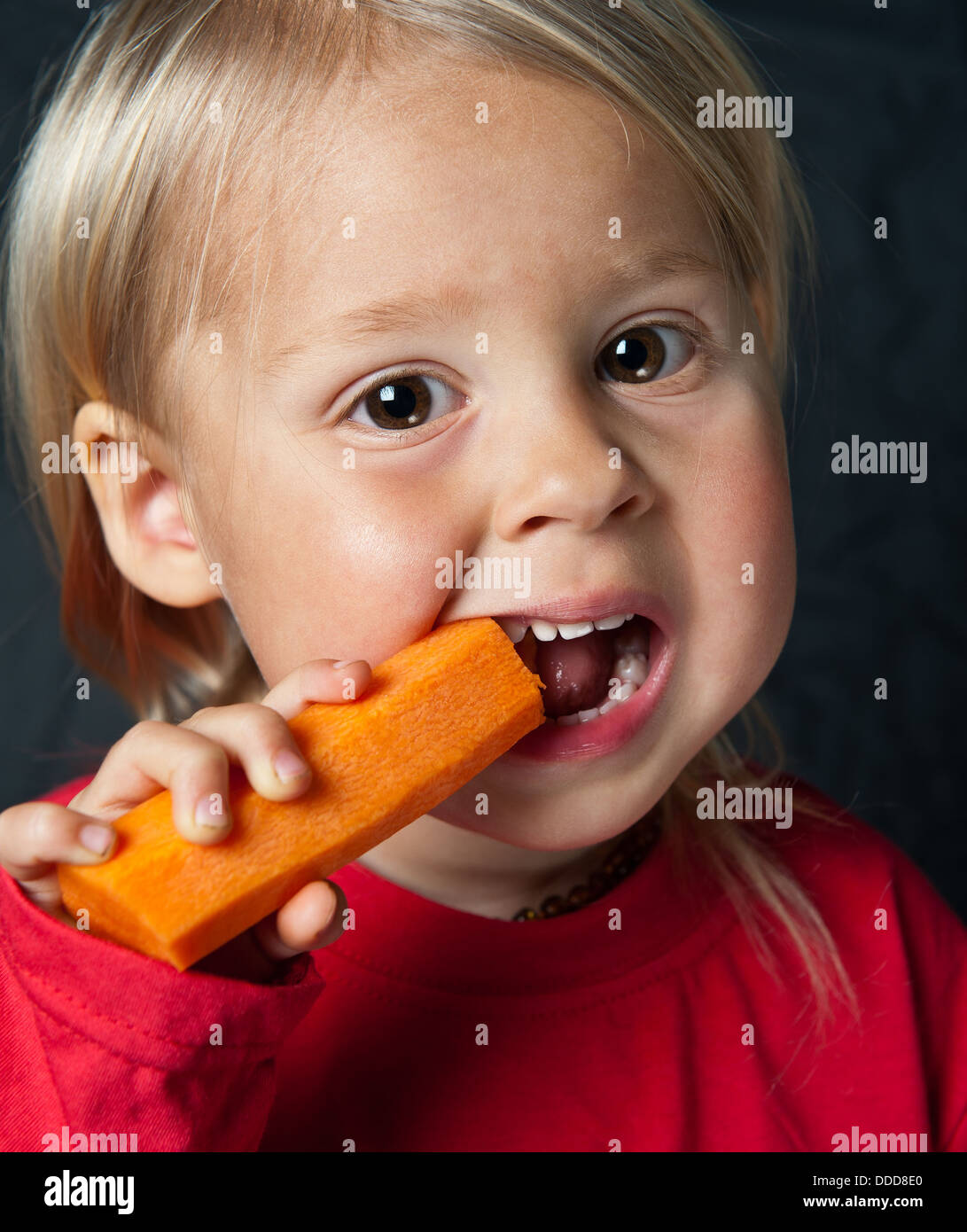 Cute young toddler eating a big fresh carrot. Also available in Black & White Stock Photo Alamy