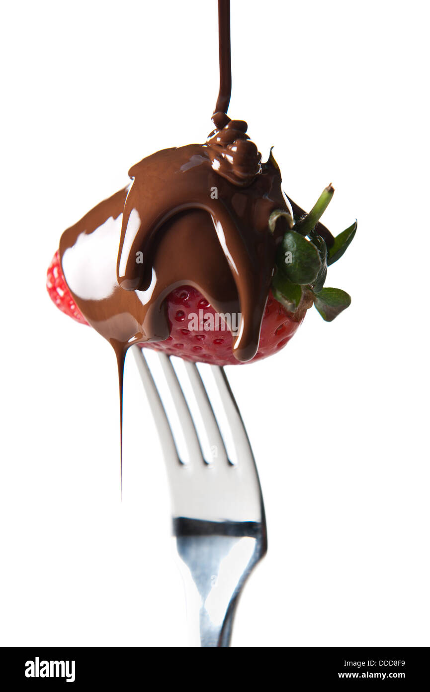 Fresh strawberry on a silver fork dripped with dark chocolate. Stock Photo