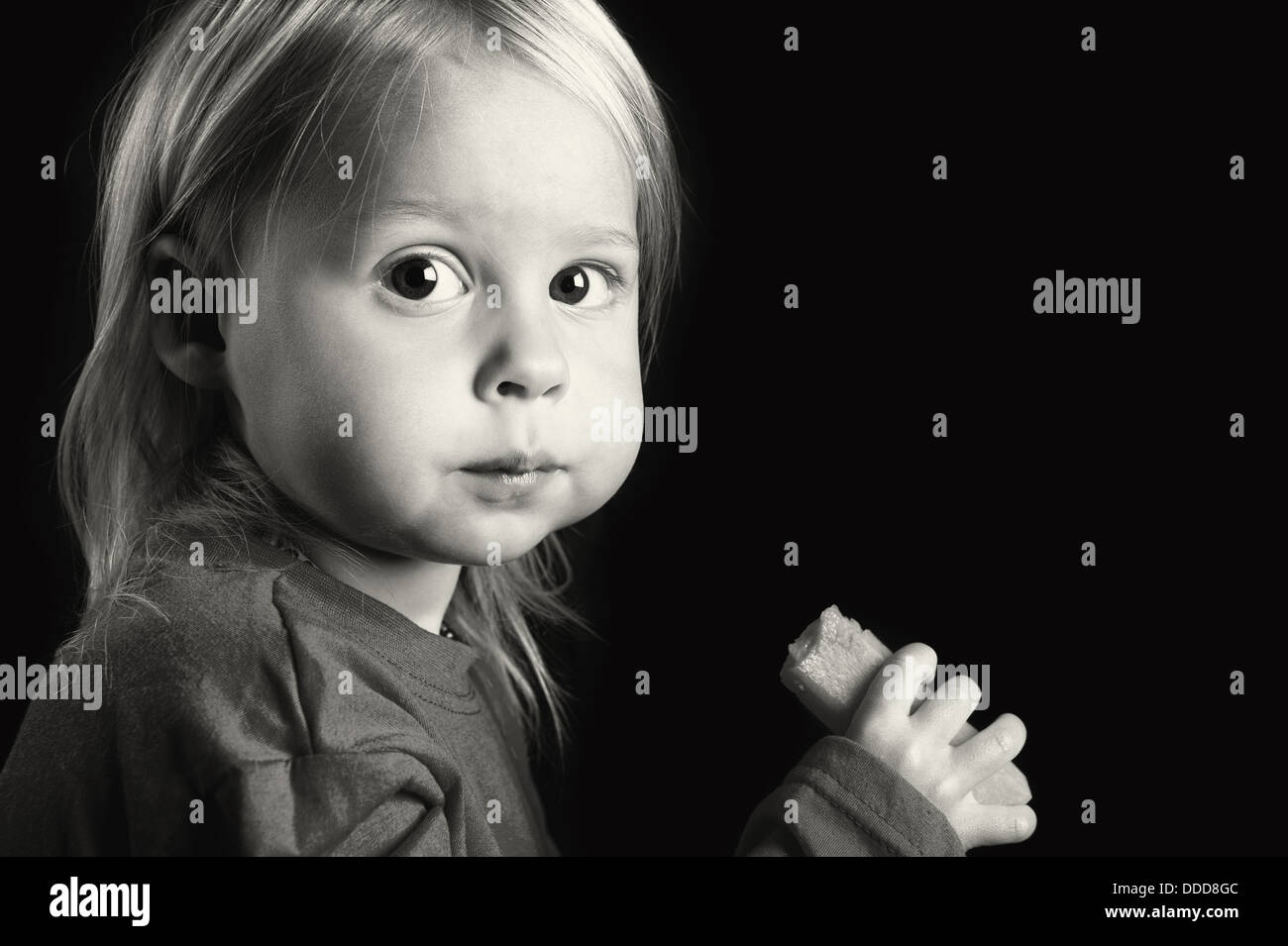 Cute young toddler eating a big fresh carrot. Also available in Black & White. Stock Photo