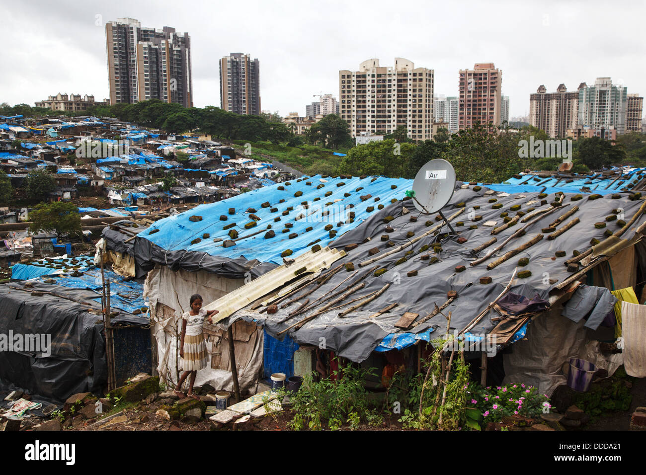 A young girl stands in front of her house covered by plastic sheets to protect from monsoon rain in the slum in Mumbai, India Stock Photo