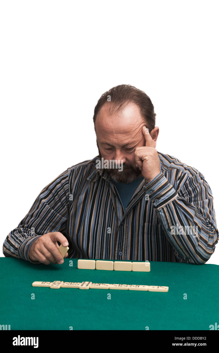 Mature man playing dominoes at a green table Stock Photo