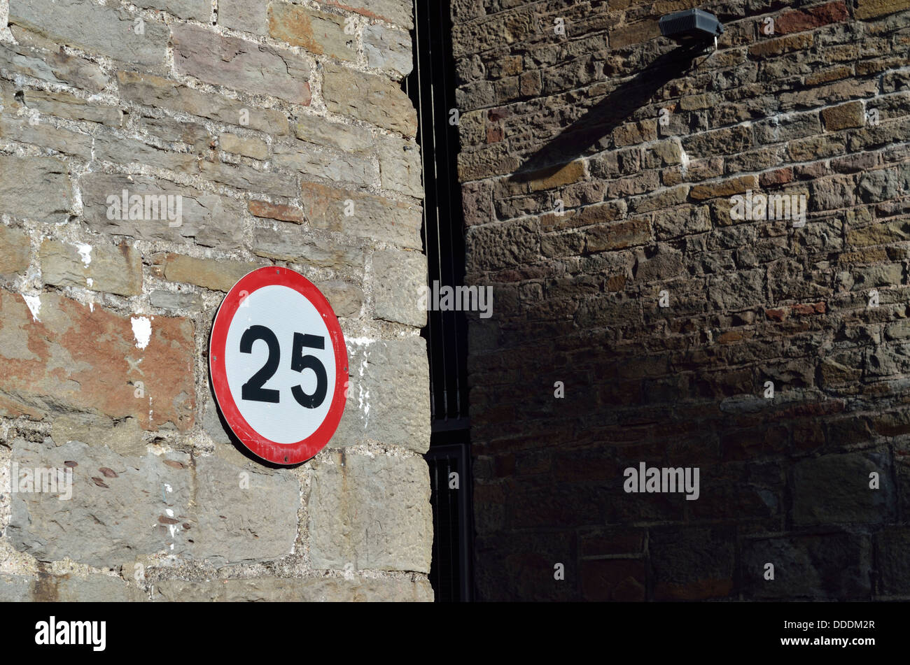 25 Mph speed restriction sign on a brick wall Stock Photo