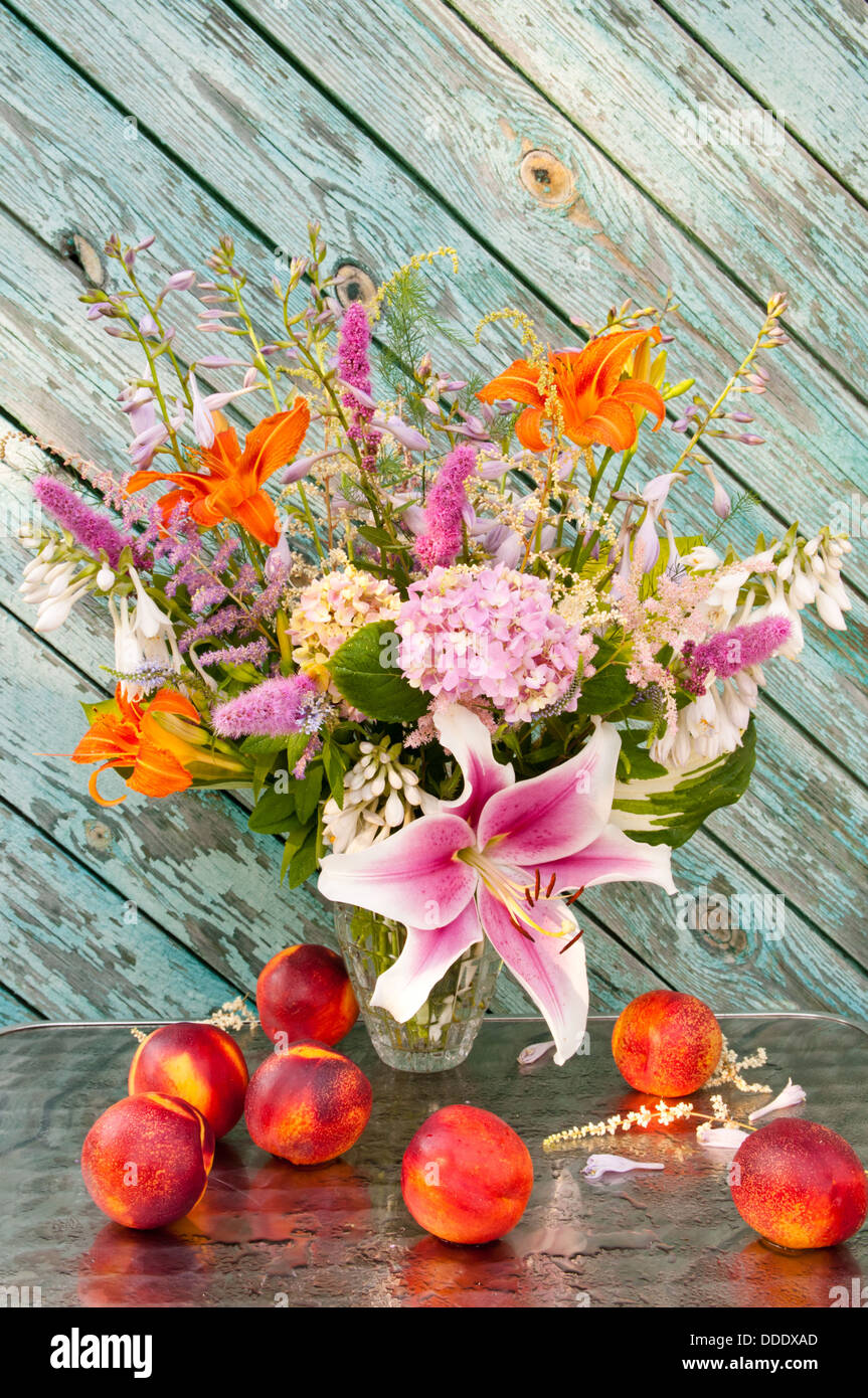 Still life bouquet of lily, hosta, astilbe, hemerocallis, pink hydrangea and nectarines. Stock Photo