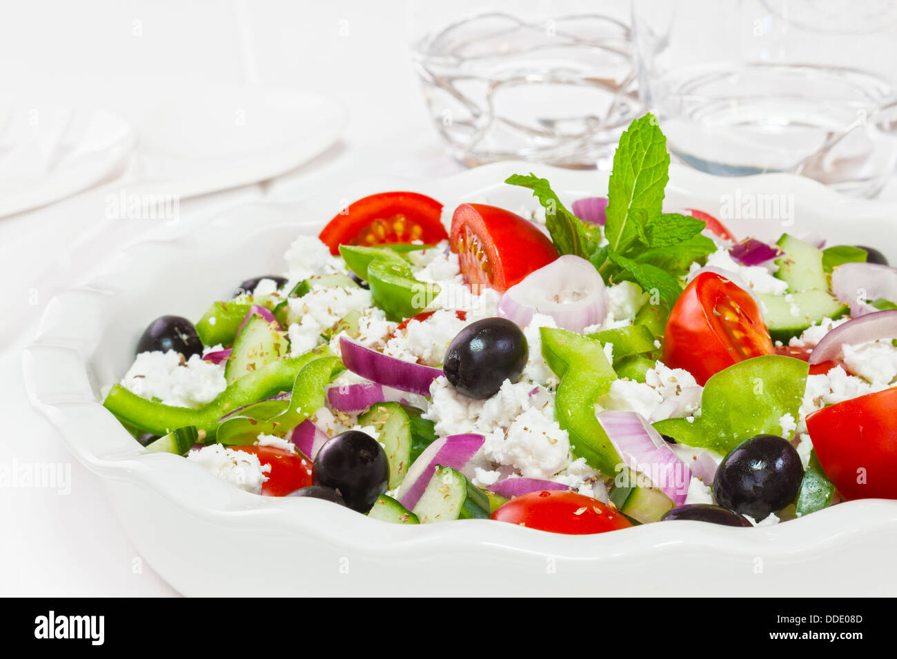 Greek salad, popular salad made from tomatoes, green pepper, cucumber, black olives, mint, oregano and feta cheese. Stock Photo