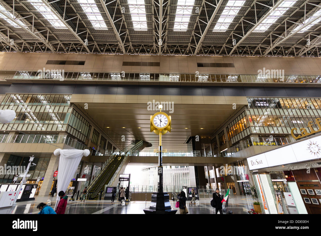 Interior of Osaka station from the middle bridge over the platform along to the main entrance atrium with the clock stand in foreground. Few people. Stock Photo