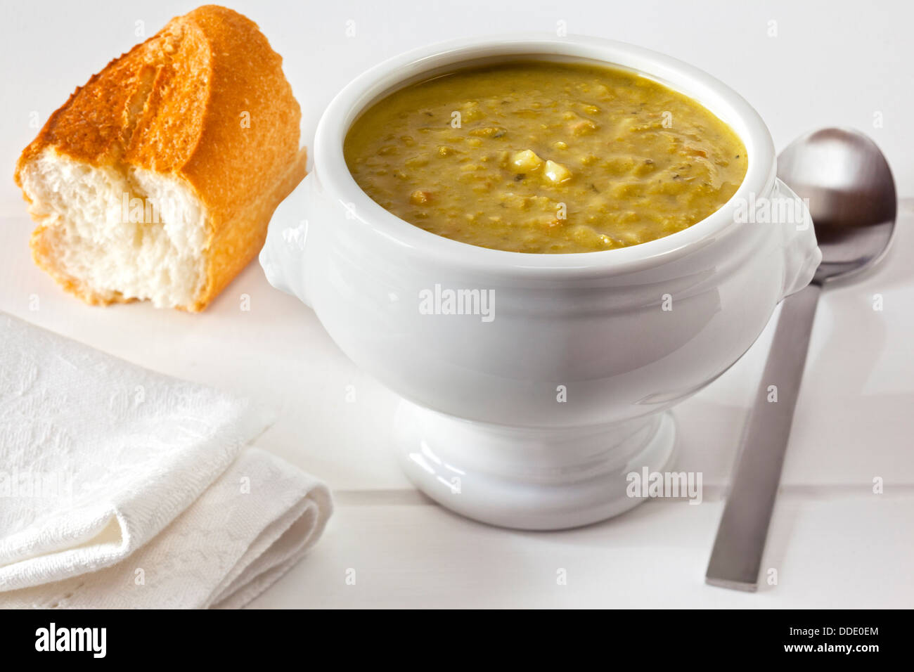 Pea Soup - a bowl of thick and hearty pea soup with a chunk of custy bread. Stock Photo