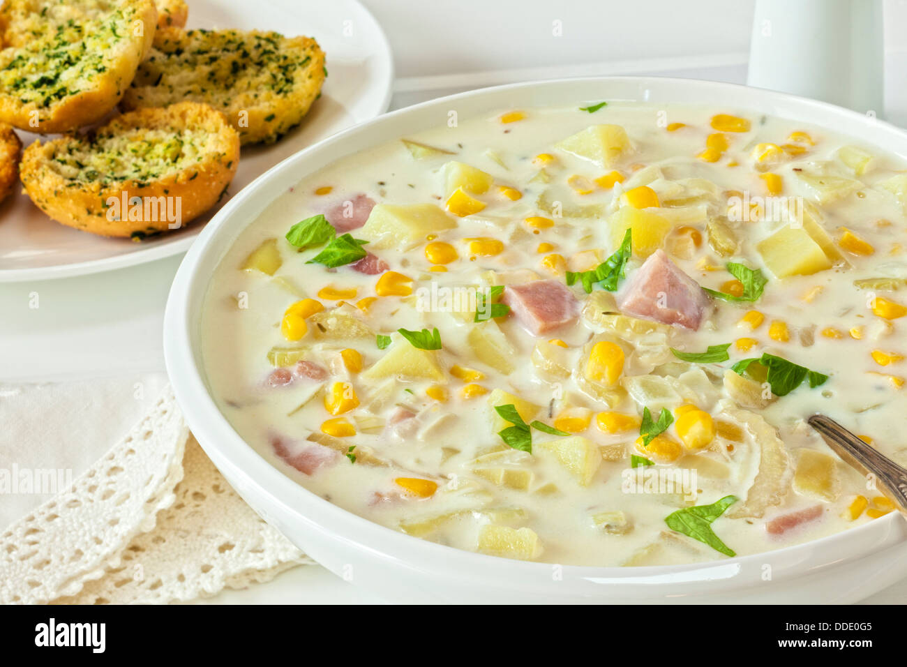 Corn Chowder - creamy corn chowder with ham and potatoes, served with crunchy garlic bread. Stock Photo