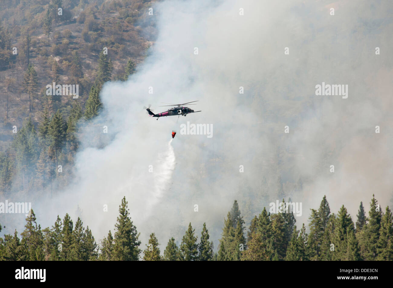 A California Air National Guards Black Hawk helicopter drops water on the Rim Fire during firefighting operations August 20, 2013 near Yosemite, CA. The fire continues to burn old growth forest and threaten Yosemite National Park. Stock Photo