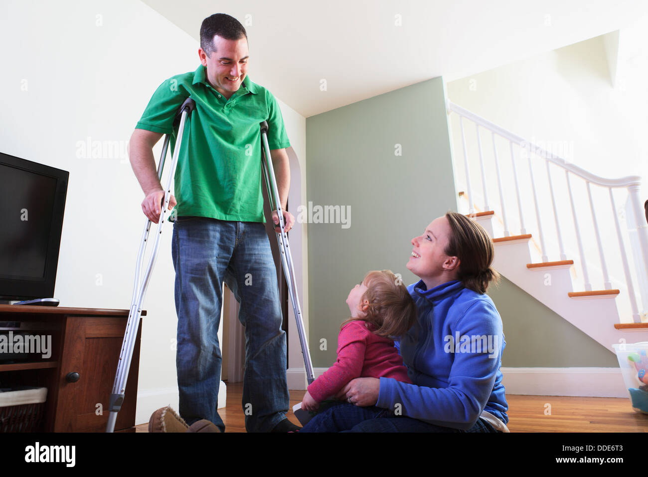 Man after anterior cruciate ligament (ACL) surgery with wife and daughter at home Stock Photo