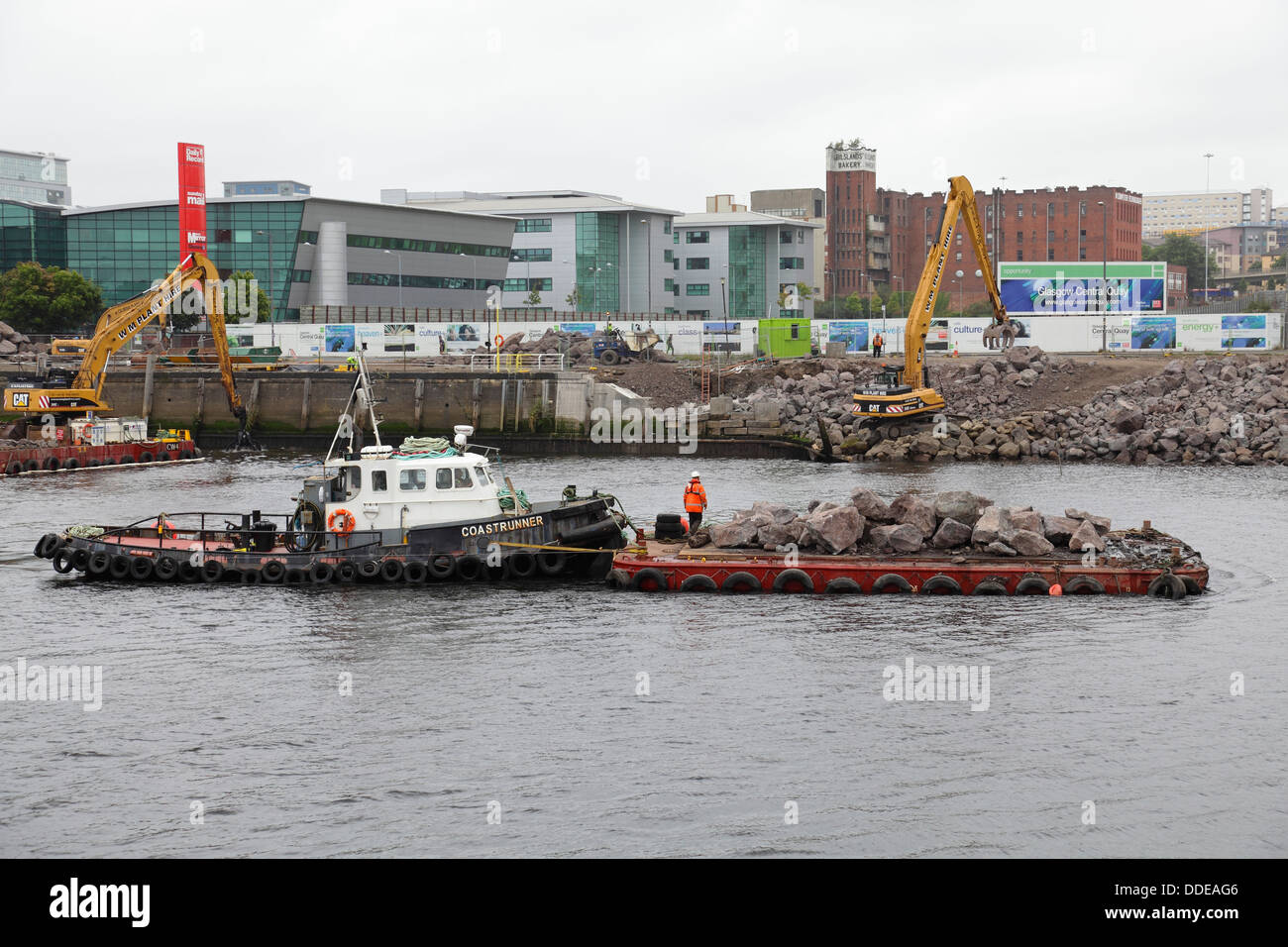 Work underway to repair the collapsed walkway at Anderston Quay on the River Clyde using a digger, tug and a barge in Glasgow, Scotland, UK Stock Photo