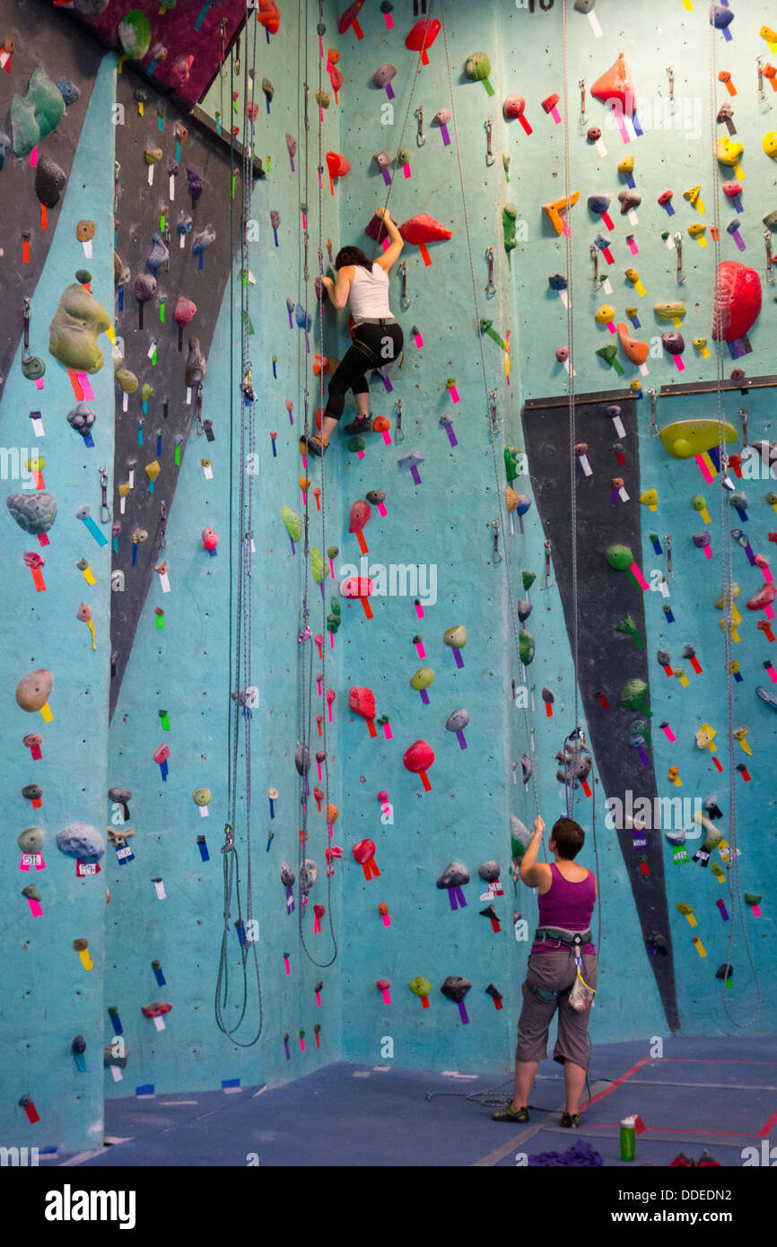 Beautiful young woman in black outfit looking at camera climbing on  practical wall in gym, bouldering, extreme sport, rock-climbing concept  Stock Photo - Alamy