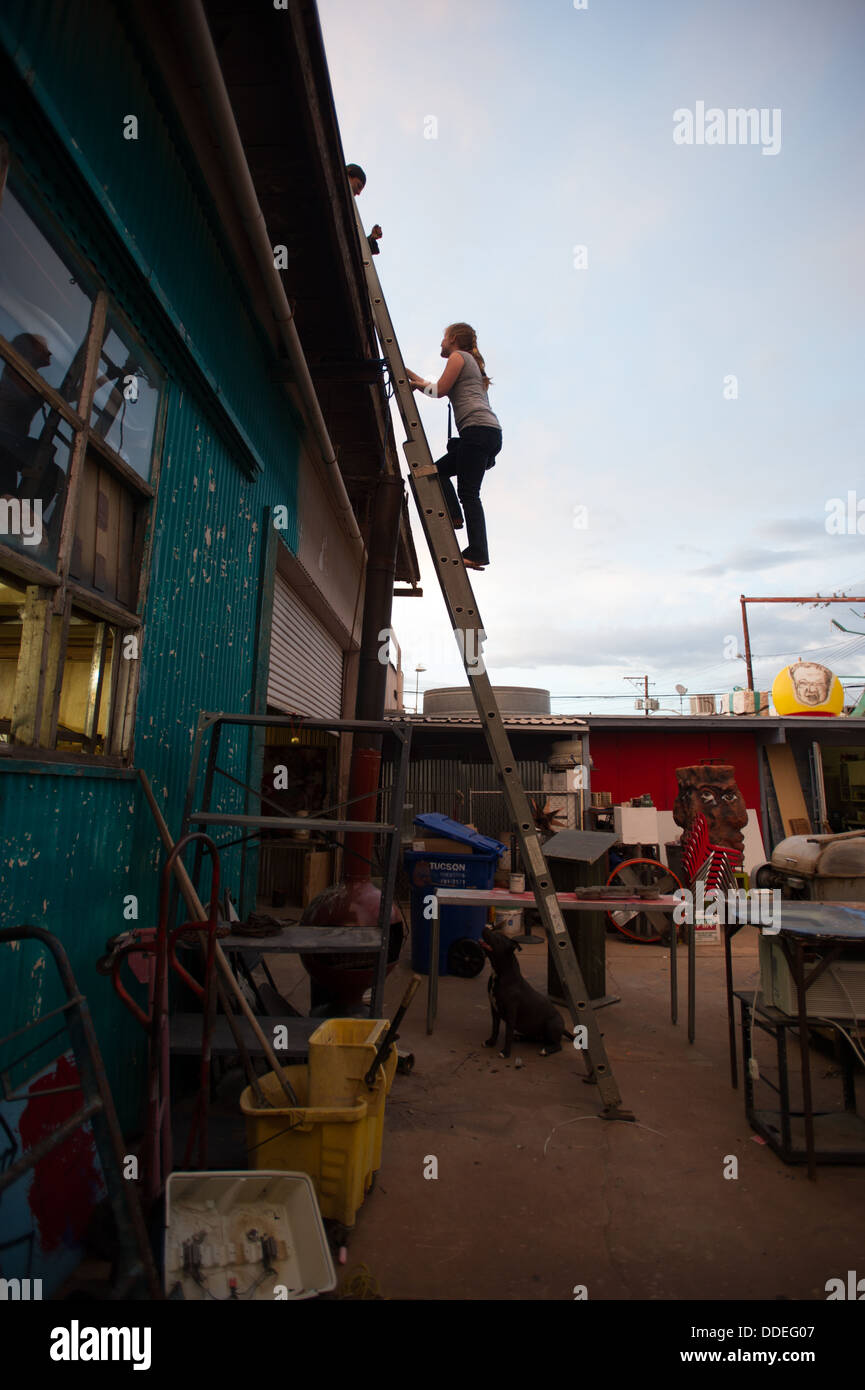 Woman climbing Ladder on Run Down warehouse Stock Photo