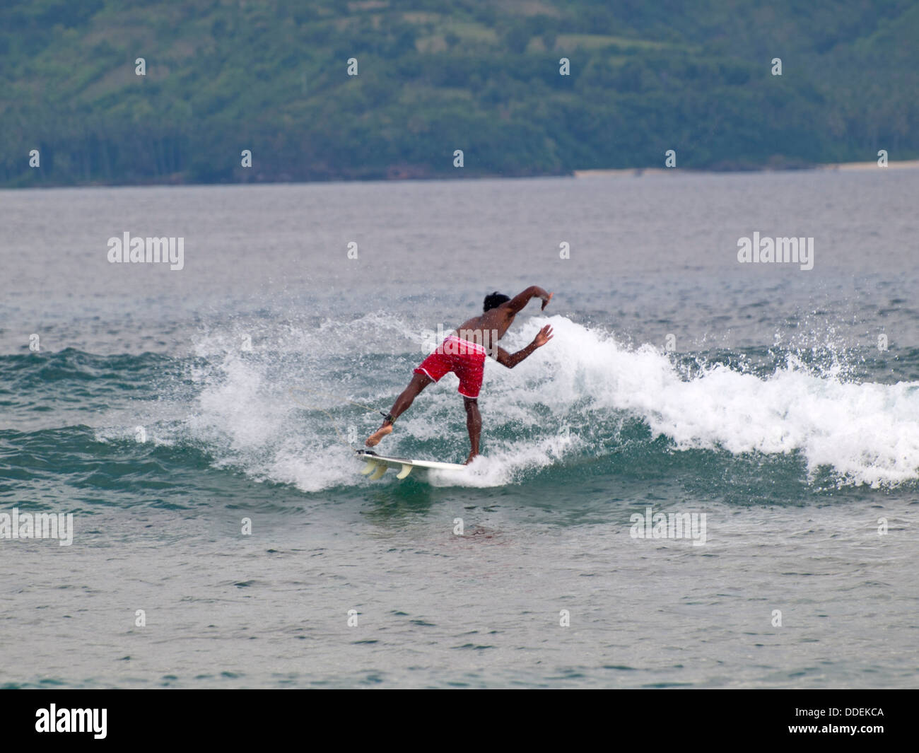 Indonesia n boy surfing the waves between Gili Trawangan and Lombok Stock Photo