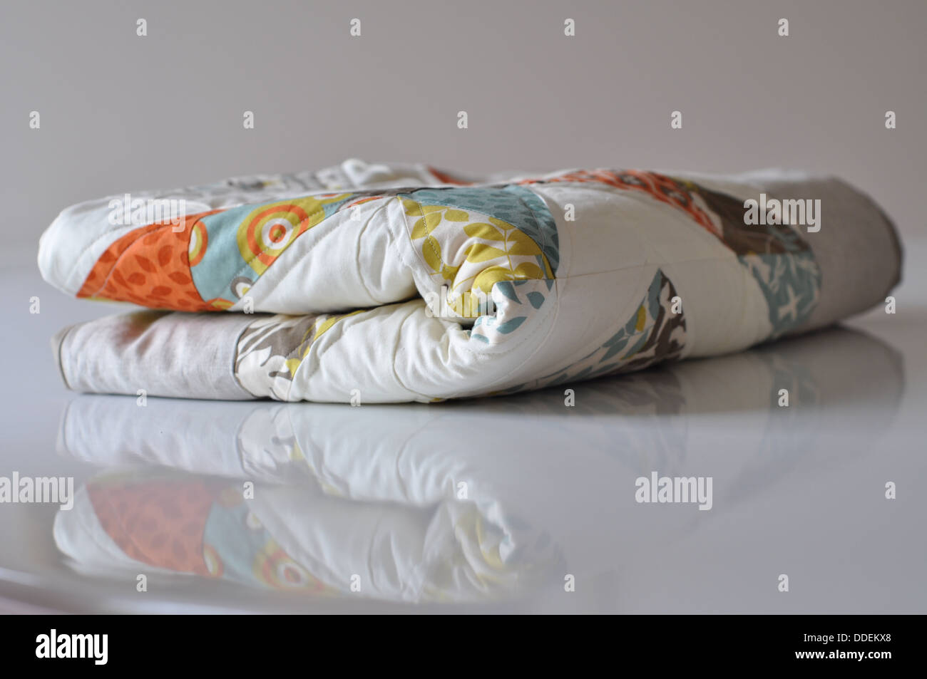 folded modern quilt on white reflective surface Stock Photo