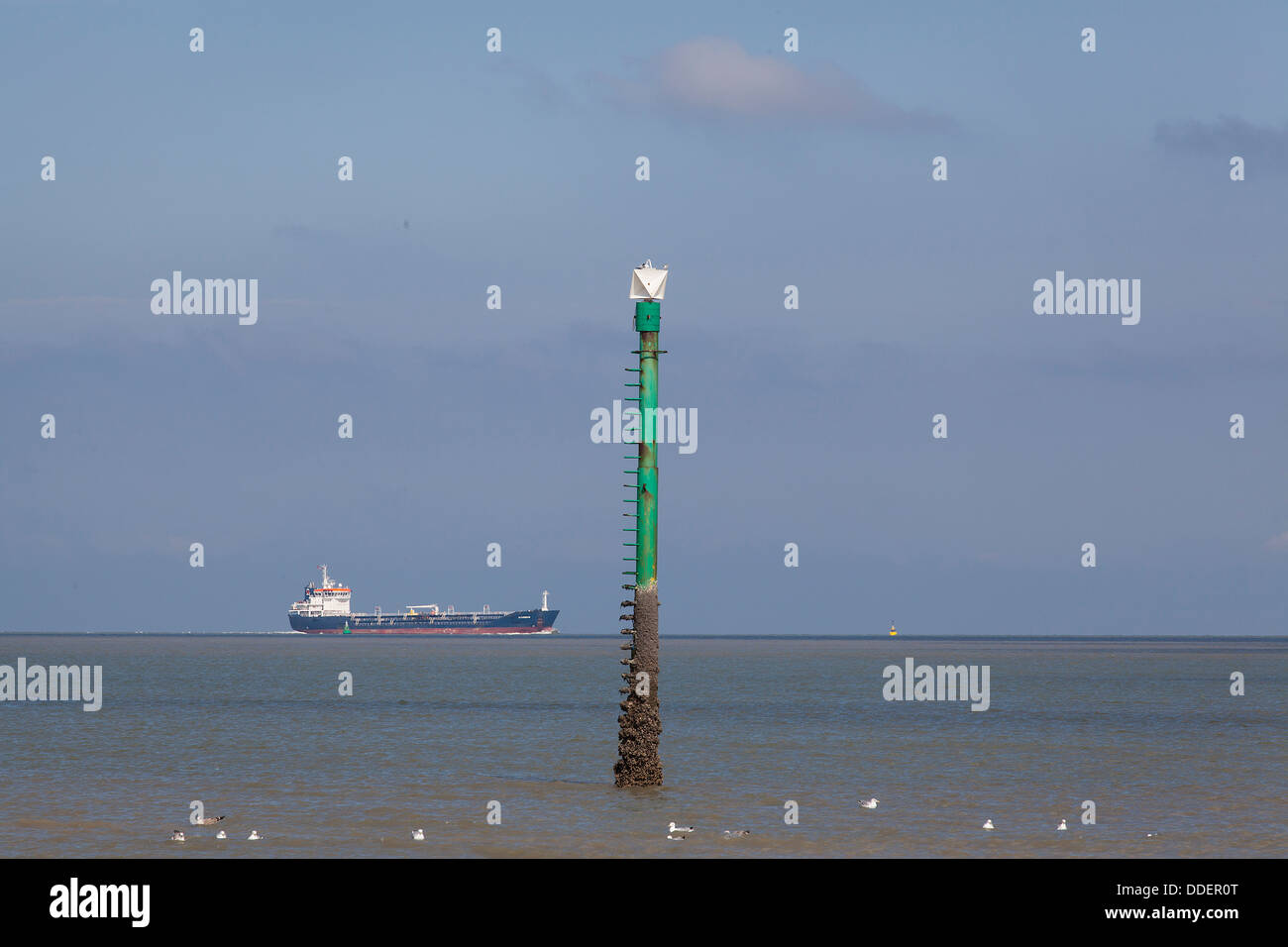 Carrier ship passing beacon close to the coast at the North Sea Stock Photo