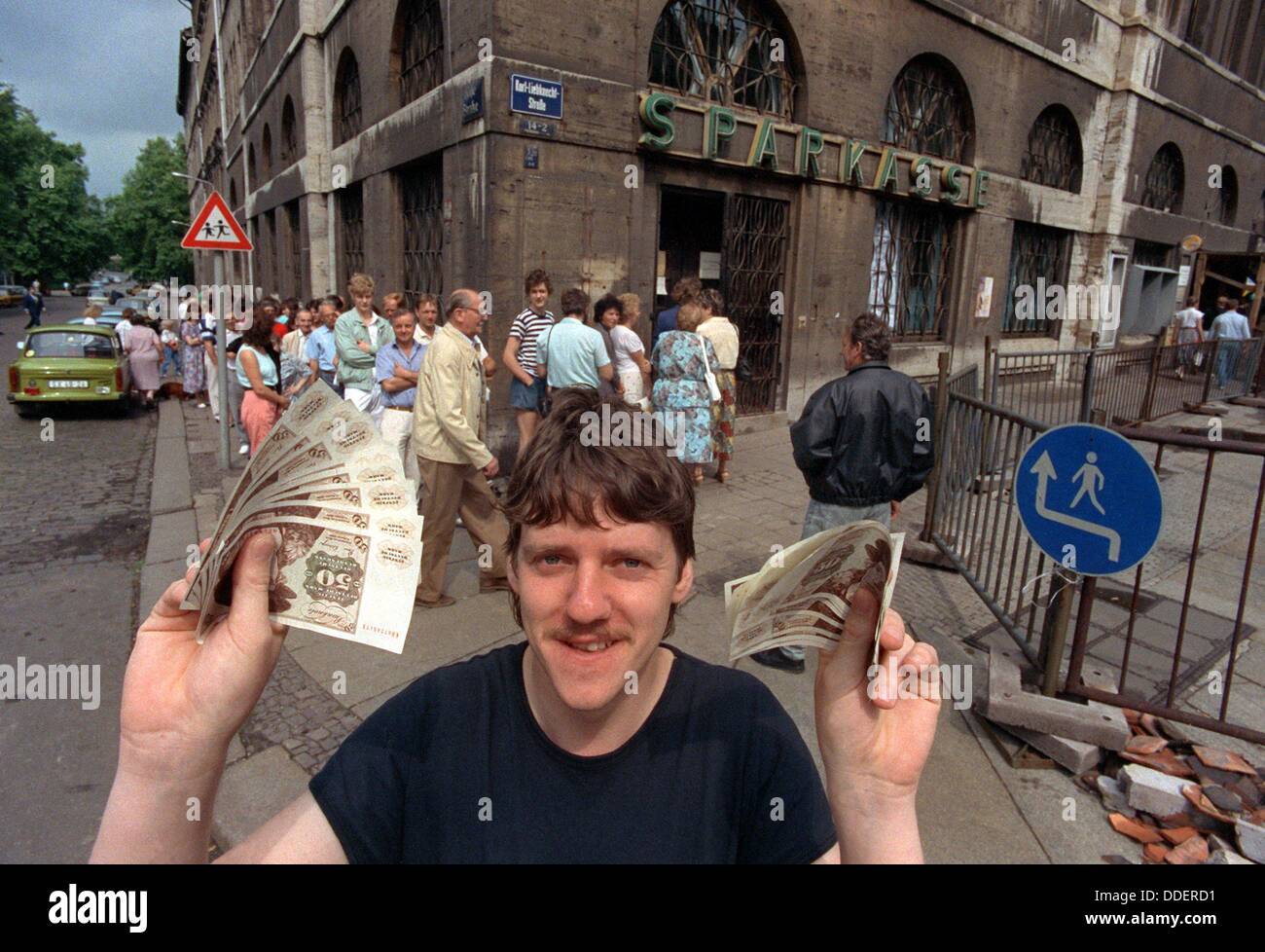 After having queued up at a bank in Leipzig for a long time, this young man is happy about his Deutsche Mark bank notes on 01 July 1990. The monetary union which was executed on 01 July 1990 was a decisive step on the way to a reunion of the two German states. On the first day of the economic, monetary and social union, there was quite a rush on the new money; some 2.6 billion Deutsche Mark were paid out to GDR citizens in the first hours. Stock Photo