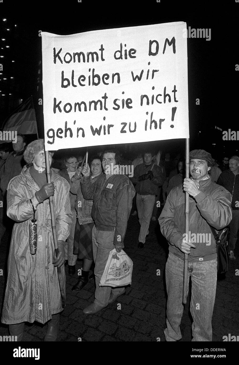 The picture shows a poster saying 'If the Deutsche Mark comes we will stay, if she doesn't come we will go to her' during a Monday demonstration in Leipzig on 12 February 1990. The demonstrators demand the introduction of the Deutsche Mark in the GDR which was put into effect in the scope of the economic, monetary and social union on 01 July 1990. It was one of the decisive steps towards the reunion of the two German states. Stock Photo