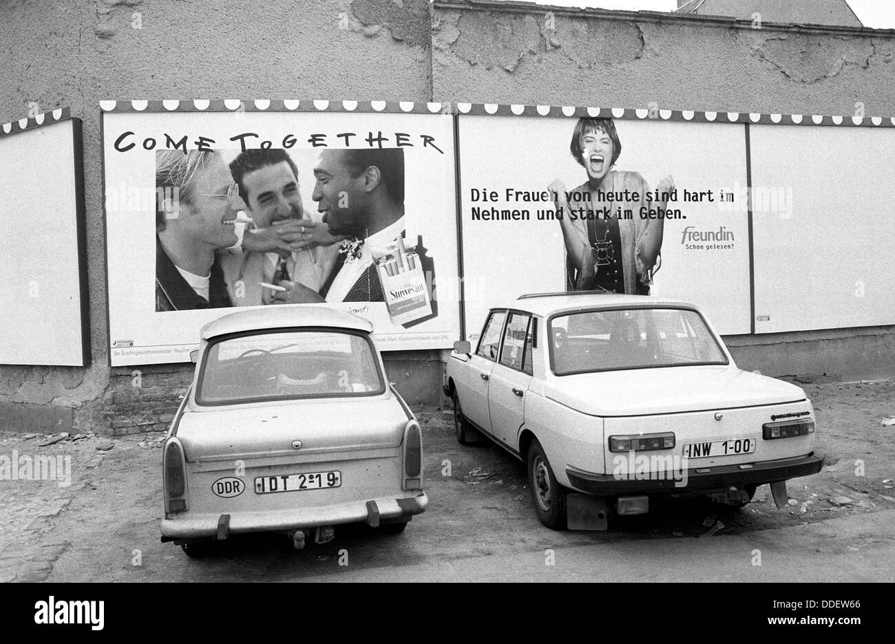 East German cars pictured under West German advertisement in Berlin, Germany. Photo: Reinhard Kaufhold Stock Photo