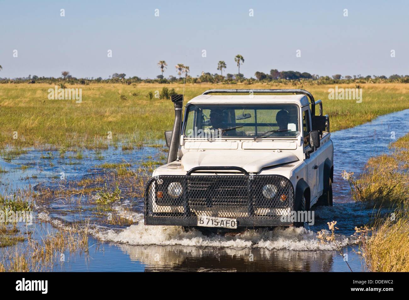 A white vehicle driving through the water in the Okavango Delta