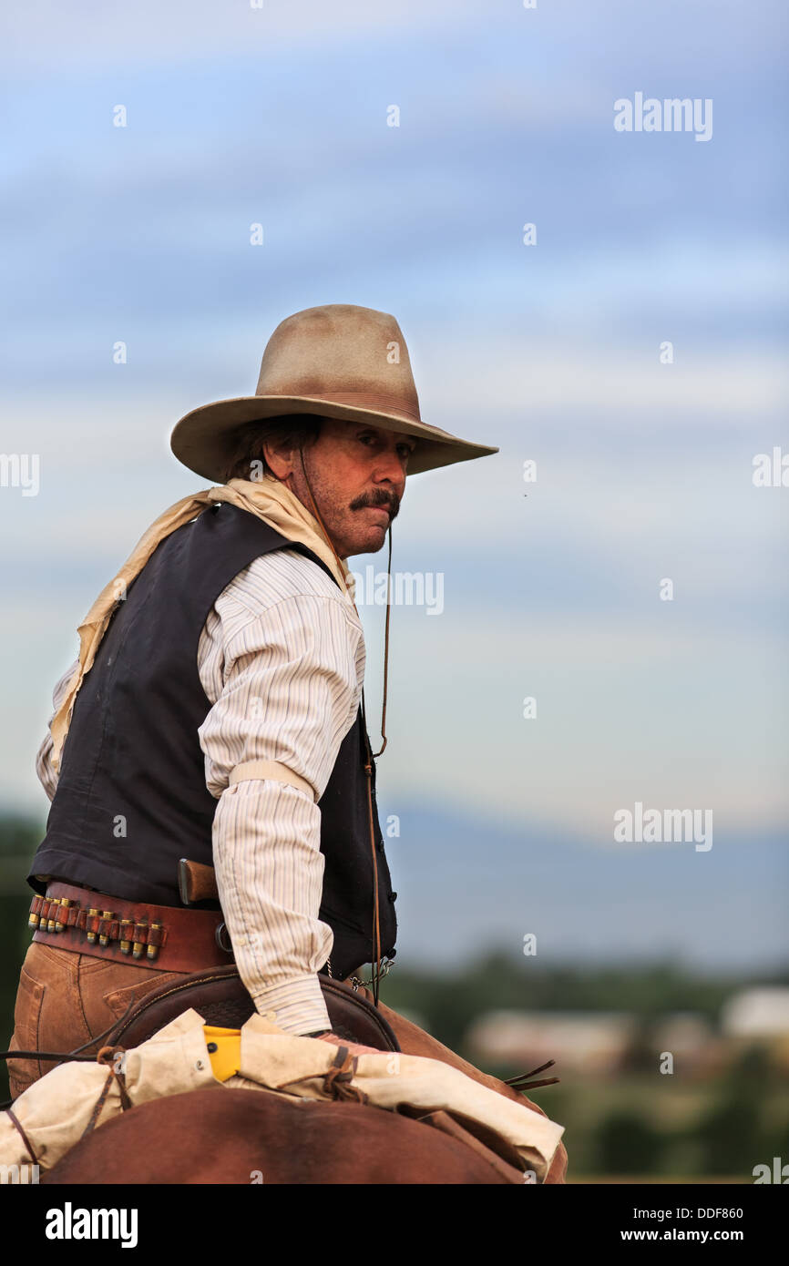 A cowboy looking back while riding his horse Stock Photo