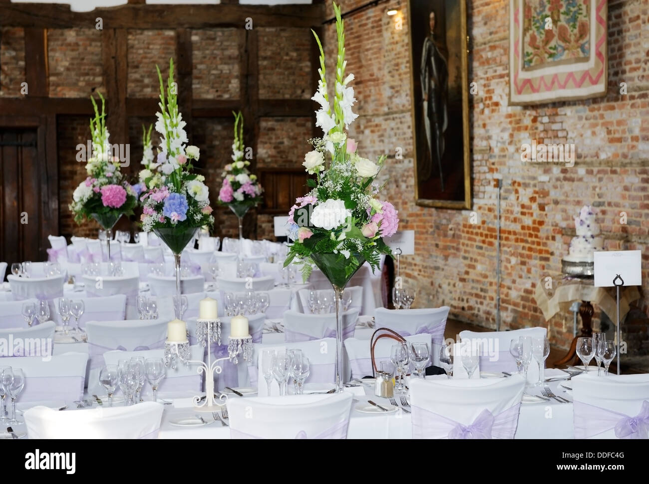 Wedding reception setting showing flower arrangements on table and purple chair covers Stock Photo