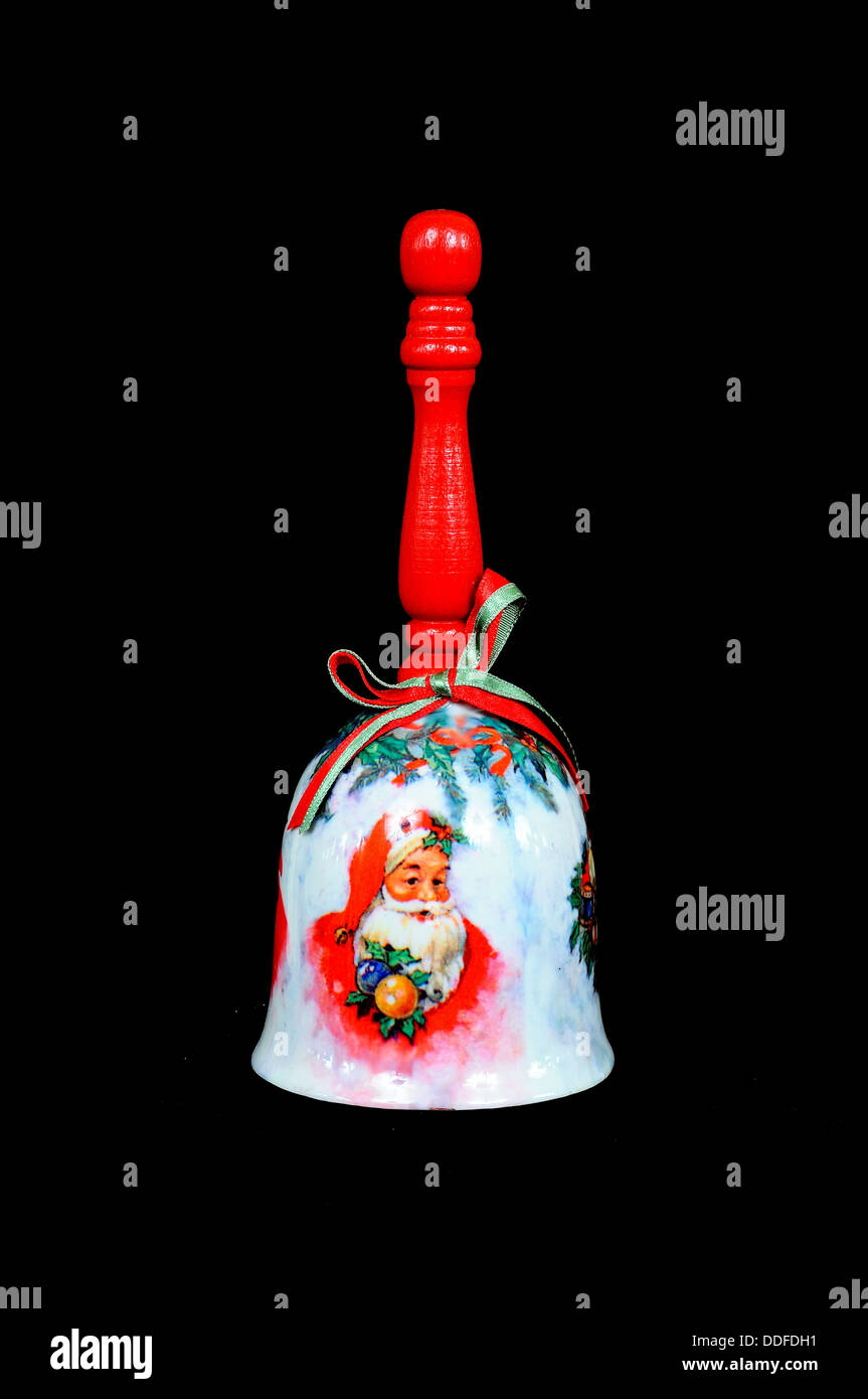 Ceramic Christmas hand bell with wooden handle on a black background. Stock Photo