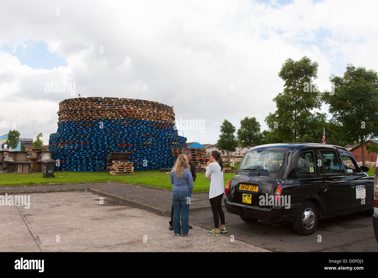 Tourists take the black taxi tour around Belfast and watch the building of a bonfire for the eleventh night to commemorate Stock Photo