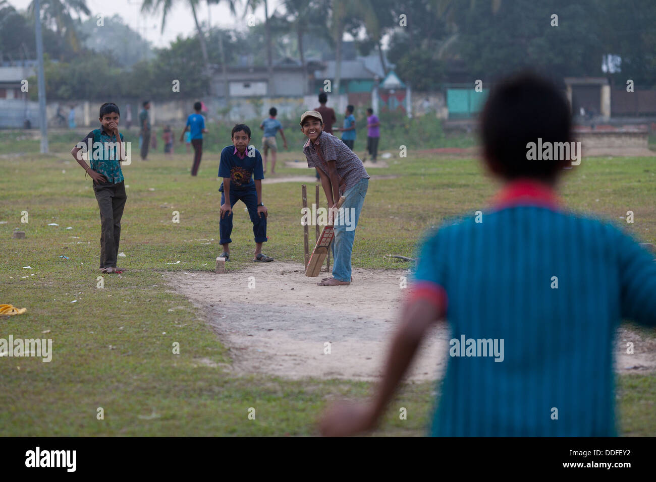 Children play cricket on a field at dusk in Srimongol, the tea growing region of Bangladesh Stock Photo