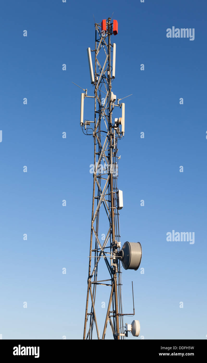 Communication radio tower with devices on blue sky background Stock Photo
