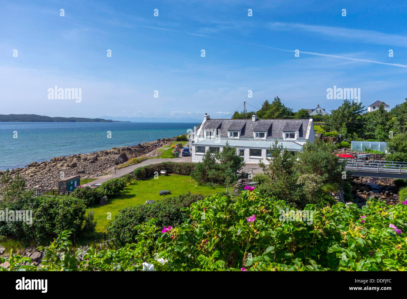 White seafront buildings with roses, croft, blue sea and sky, Gairloch, Northwest Scotland Stock Photo
