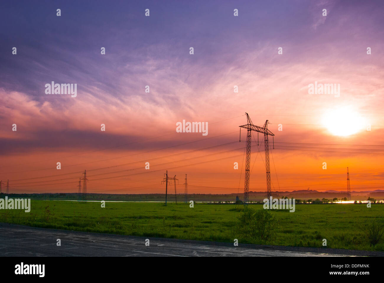 Electricity pylons and wires in a green field against evening sky Stock ...