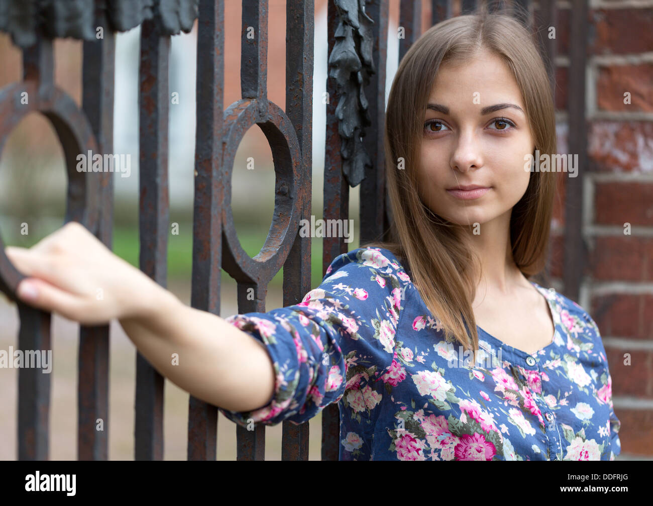Portrait of a beautiful girl near the old rusty wrought fence. Stock Photo