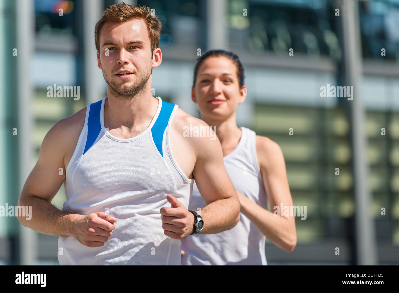 Young sport couple jogging in city environment - man first Stock Photo