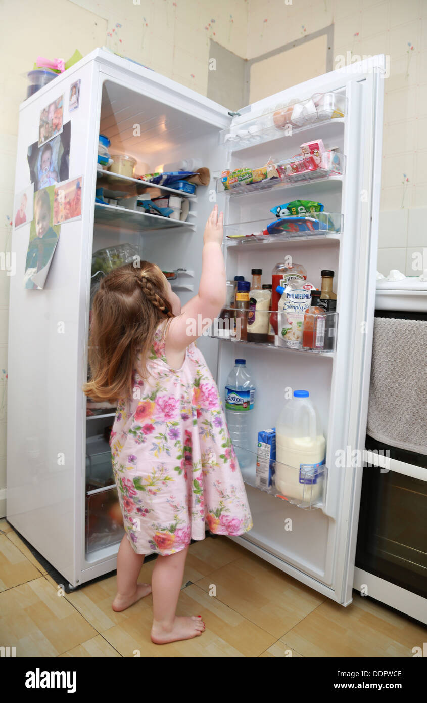 Toddler girl helping herself to food in the fridge Stock Photo Alamy