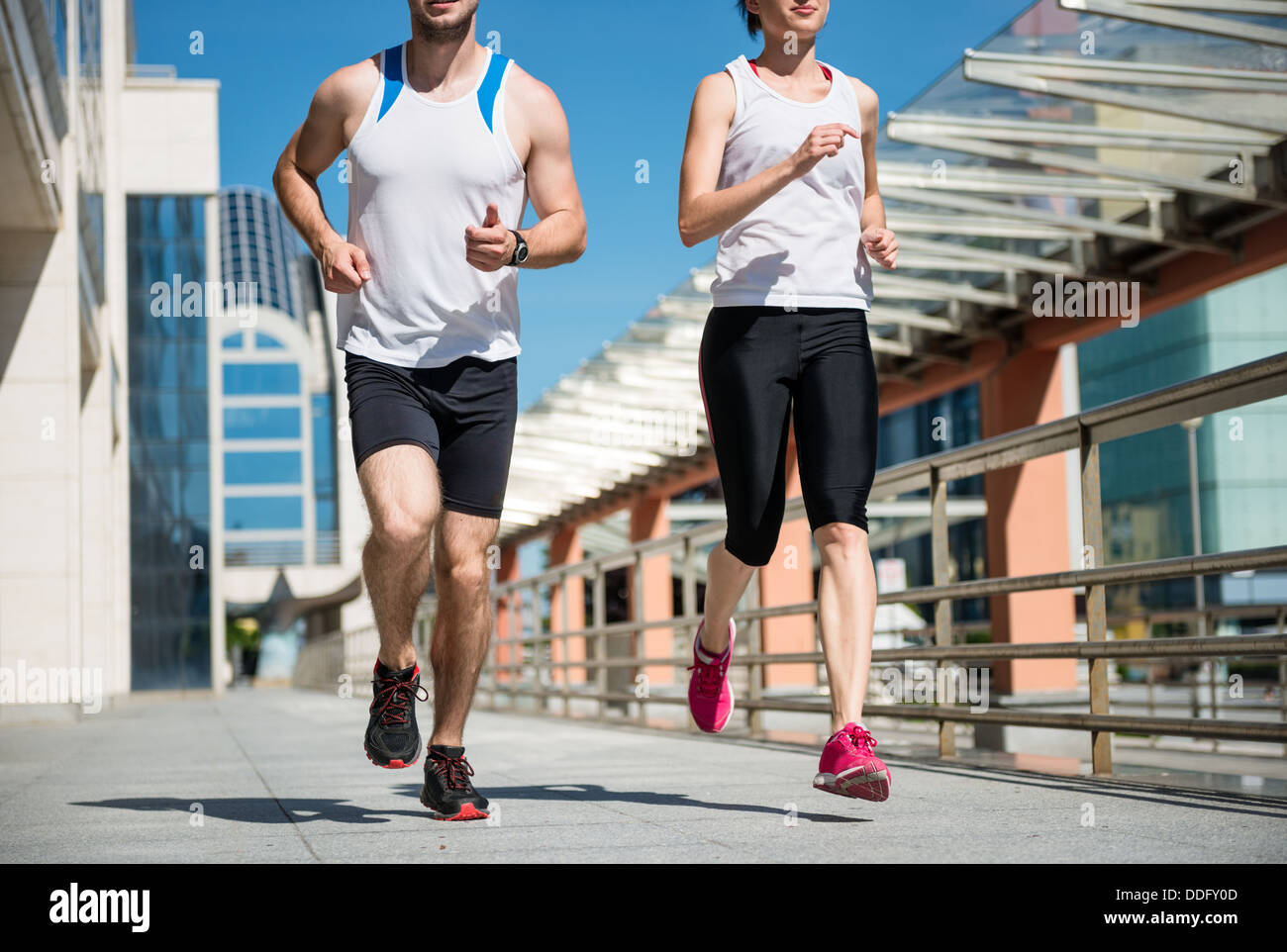 Young sport couple jogging together in city environment - crop Stock Photo