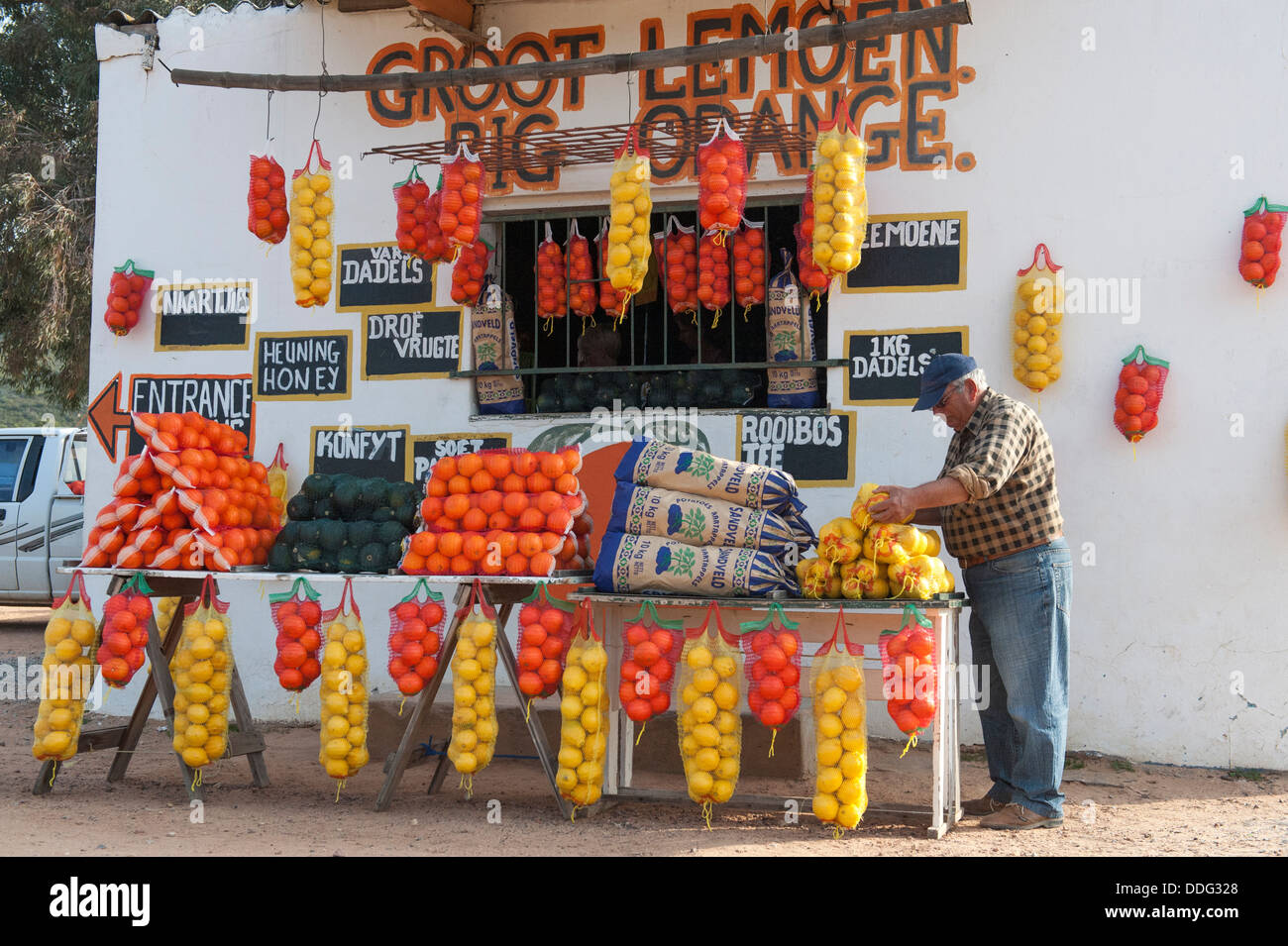 Farmer selling oranges and other farm produce in front of a farm-stall, Citrusdal, Western Caper, South Africa Stock Photo