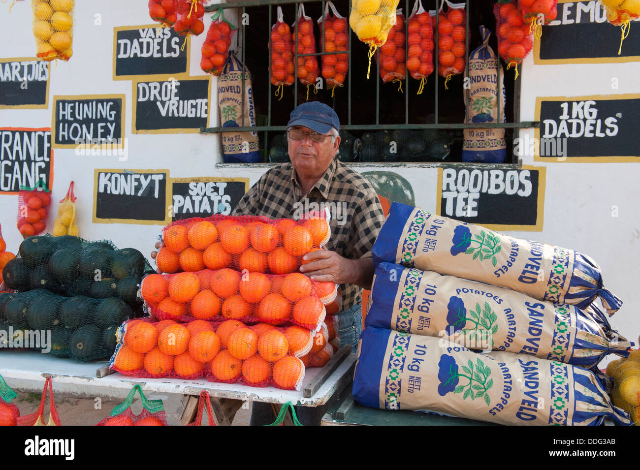 Farmer selling oranges and other farm produce in front of a farm-stall, Citrusdal, Western Caper, South Africa Stock Photo