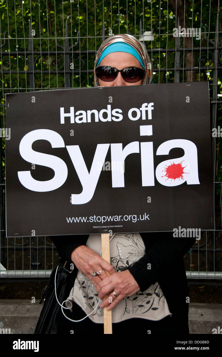 Demonstration against any intervention in Syria.  A Muslim woman wearing a headscarf and sunglasses holds a placard . Stock Photo