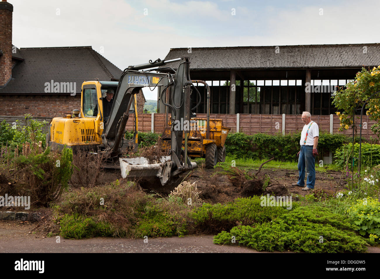 self building house, preparing site by stripping back vegetation and topsoil from garden with JCB digger Stock Photo